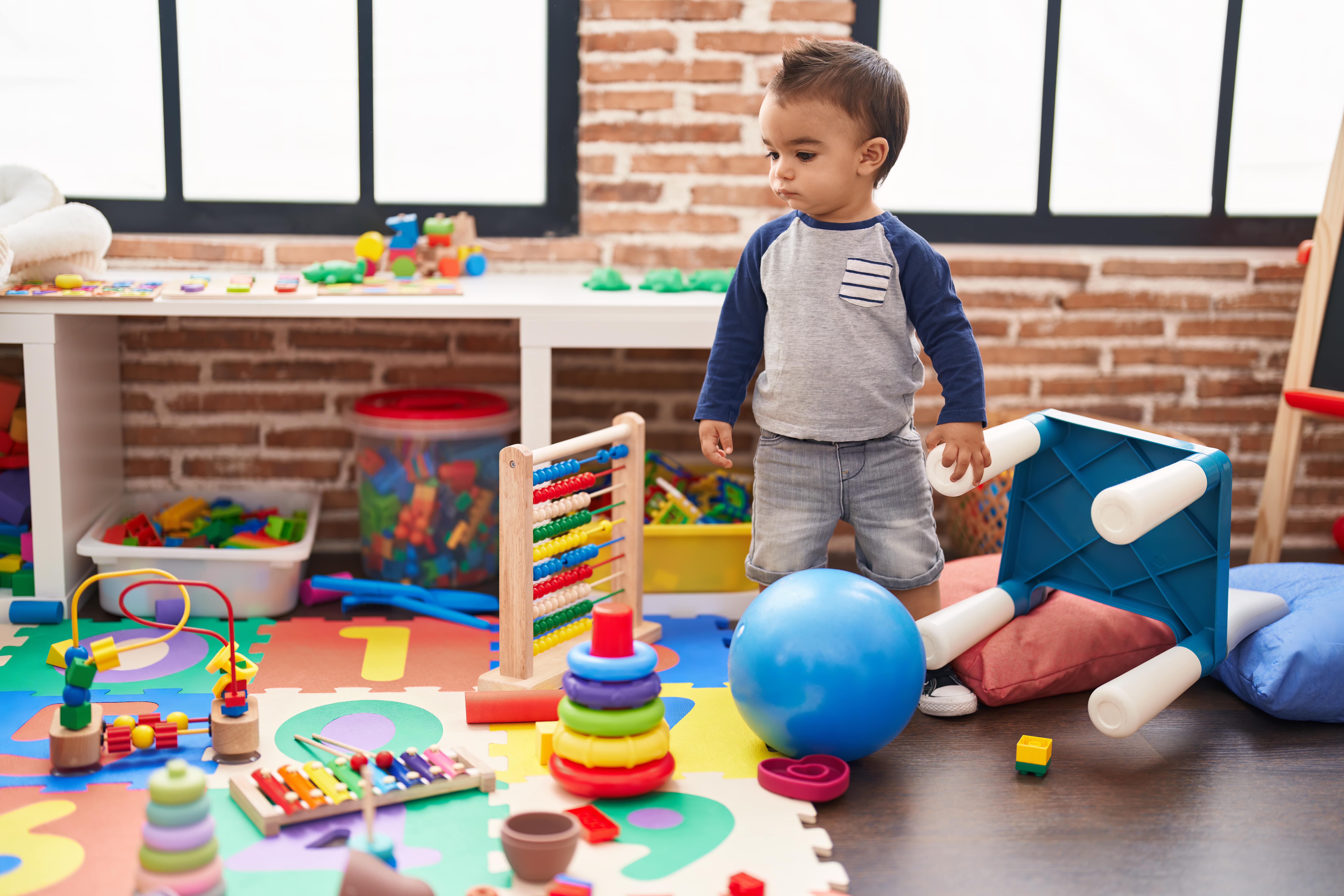 adorable-hispanic-toddler-standing-with-serious-expression-kindergarten-min